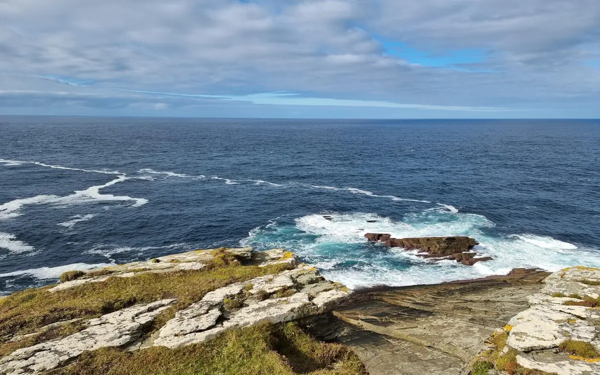 Flat rock ledges above a dark blue sea with white surf