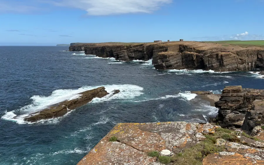 Layered sandstone cliffs and white surf, a flat rock ledge in front